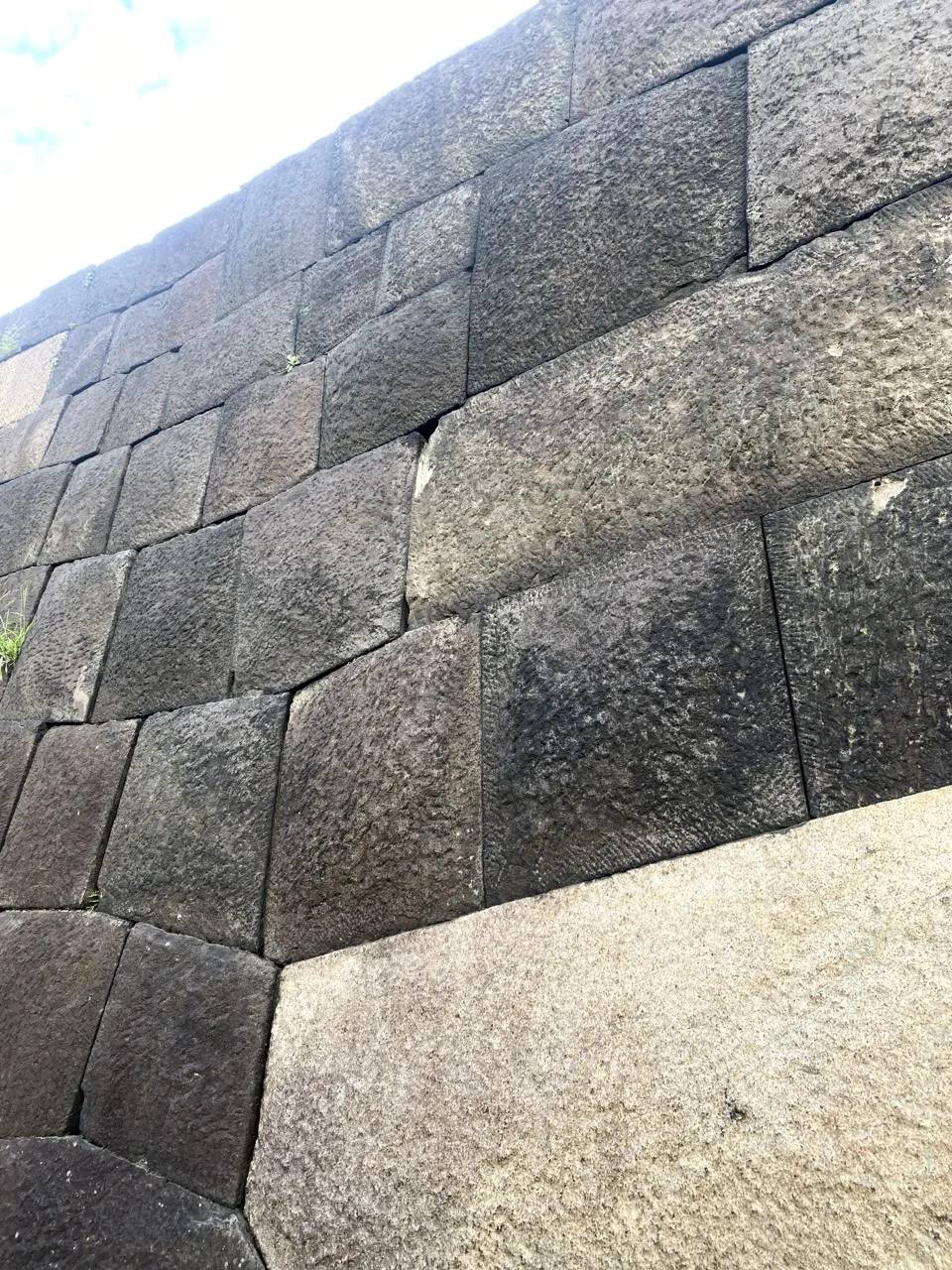 大きさの違う切石を積んだ石垣を斜めから見た画面。継ぎ目に影が落ち、右下に明るい石の面がある。
