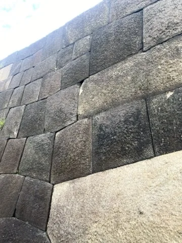大きさの違う切石を積んだ石垣を斜めから見た画面。継ぎ目に影が落ち、右下に明るい石の面がある。