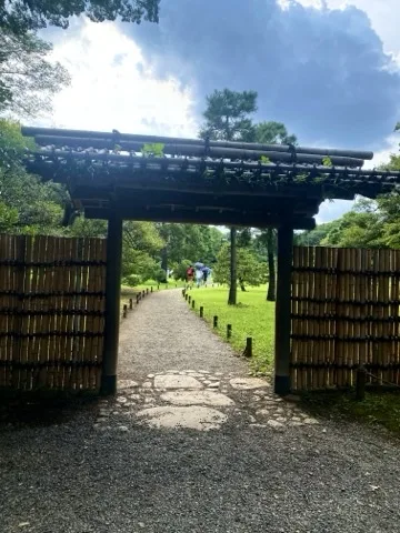 高台にある木の門を見上げるように撮り、奥へ続く石畳の道が見える。