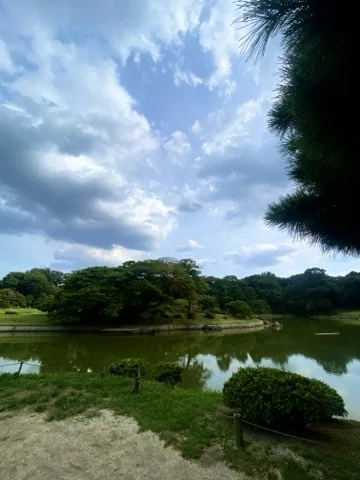 曇り空の下、池と対岸の石組みを撮った写真。